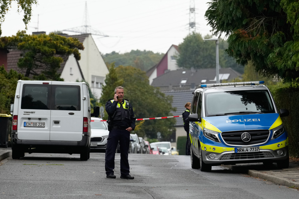 A police officer talks on his phone at a street in Herdecke, Germany, Tuesday, Oct. 7, 2025, after the newly elected mayor of Herdecke, Iris Stalzer, has been found critically injured in her apartment. (AP Photo/Martin Meissner)