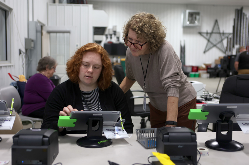 Election workers Kirsten White, left, and Angie Wilhoit, right, look at a tablet together in a vote center during a primary election on Tuesday, May 5, 2026, in West Lafayette, Ind. (AP Photo/Cara Penquite)