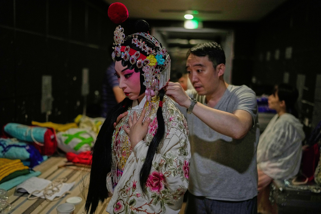 Peking Opera actress Zhang Wanting gets help putting on a costume backstage before a show in Beijing, China, Sunday, Sept. 7, 2025. (AP Photo/Mahesh Kumar A.)