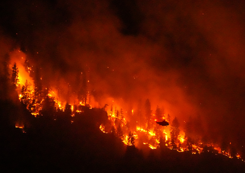 FILE - A helicopter conducting night operations prepares to drop water on the Quilpituk Creek wildfire burning on the west side of Okanagan Lake near Fintry, British Columbia, Aug. 3, 2026. (Darryl Dyck/The Canadian Press via AP, File)