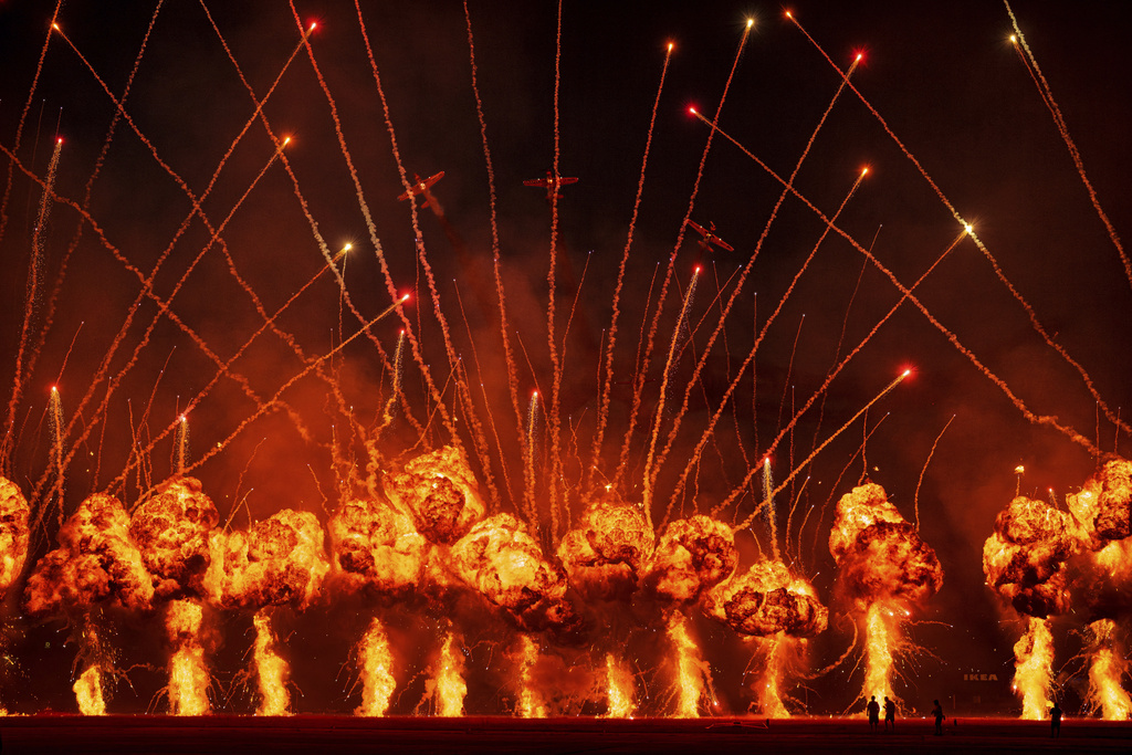 Pyrotechnics go off as the Air Bandits aerobatic team, led by Lithuanian pilot Jurgis Kairys, performs above the runway of the Aurel Vlaicu airport, at the end of the first day of the Bucharest International Air Show, BIAS 2025 in Bucharest, Romania, Saturday, Aug. 30, 2025. (AP Photo/Andreea Alexandru)