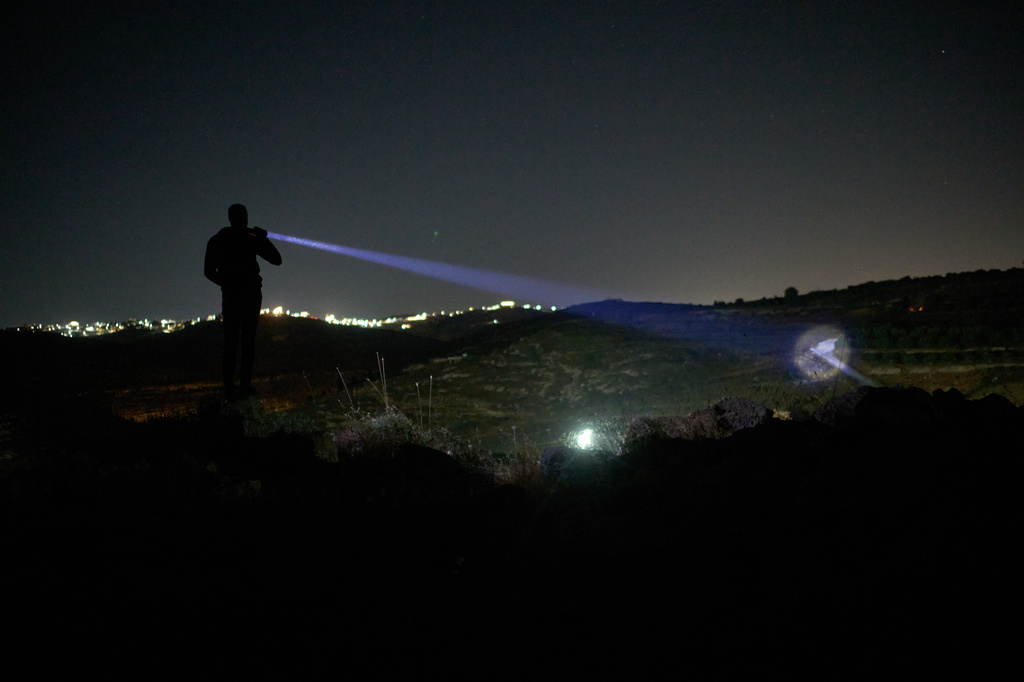 A Palestinian uses a flashlight as he takes part in a night watch to protect their village against Israeli settler attacks in the West Bank village of Sinjil, Thursday, July 16, 2026. (AP Photo/Leo Correa)