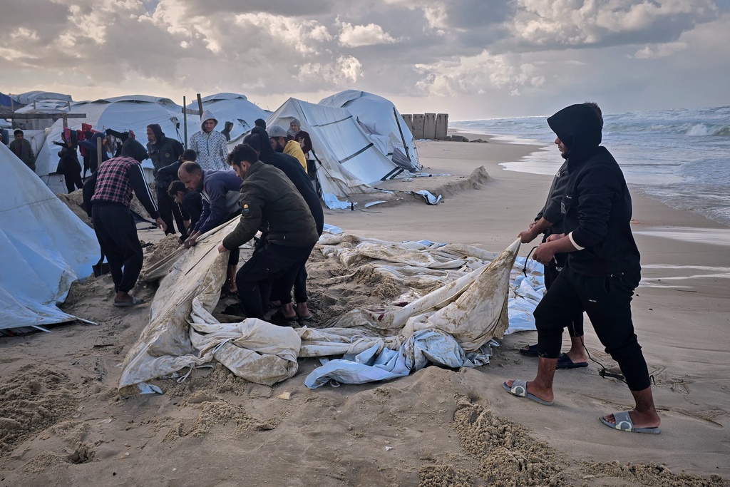 Palestinians try to recover their tent after overnight rainfall flooded their beachside tent camp in Khan Younis, in the southern Gaza Strip, Sunday, Dec. 28, 2025. (AP Photo/Mohammad Jahjouh)
