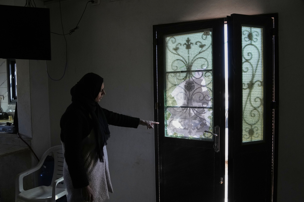 Wafaa Rabie, 30, shows the door of her house that was damaged during an Israeli settlers attack in the town of As Samu', near the West Bank city of Hebron, Tuesday, Dec. 23, 2025. (AP Photo/Mahmoud Illean)