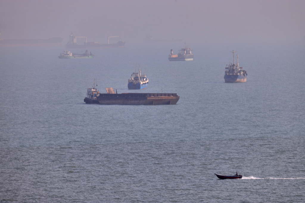 A small boat sails past cargo ships and other commercial vessels anchored in the Strait of Hormuz off Bandar Abbas, Iran, Wednesday, Aug. 5, 2026. (Amirhosein Khorgooi/ISNA via AP)