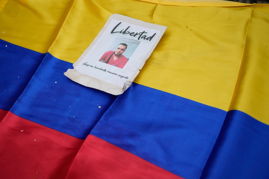 A photo of Colombian Humberto Ramirez imprisoned in Venezuela lies on a Colombian flag during a protest for Colombians to be released from Venezuelan prisons, near the Atanasio Girardot Binational Bridge, in Villa del Rosario, Colombia, Friday, March 13, 2026. (AP Photo/Fernando Vergara)