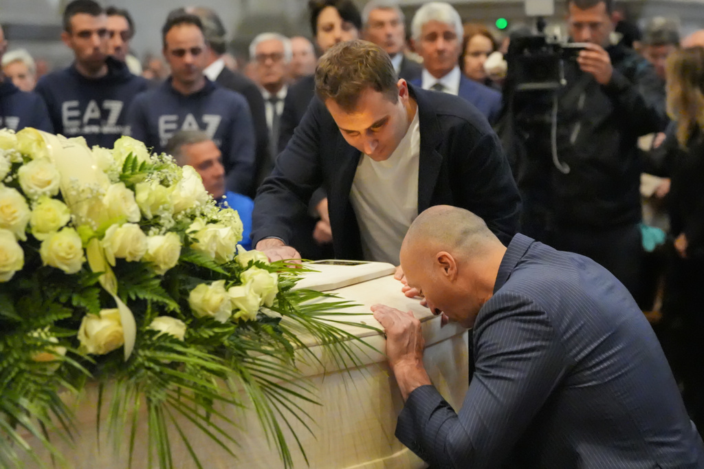 Niccolò Zanardi, son of Alex Zanardi, Italian auto racing champion-turned-Paralympic gold medalist, and friend Federico Zanelli, bottom right, mourn over the coffin during Alex Zanardi's funeral ceremony inside the Basilica of Santa Giustina, Padua, Italy, Tuesday, May 5, 2026. (Claudio Furlan/LaPresse via AP)
