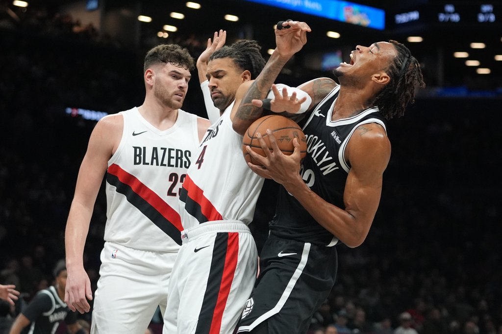 Portland Trail Blazers' Matisse Thybulle (4) and Donovan Clingan (23) defend Brooklyn Nets' Nic Claxton (33) during the first half of an NBA basketball game Monday, March 16, 2026, in New York. (AP Photo/Frank Franklin II)