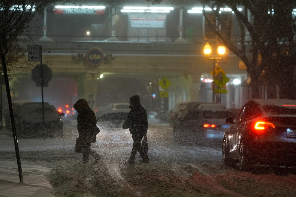 Bundled up people walk across the street Saturday, Nov. 29, 2025, in Chicago. (AP Photo/Kiichiro Sato)