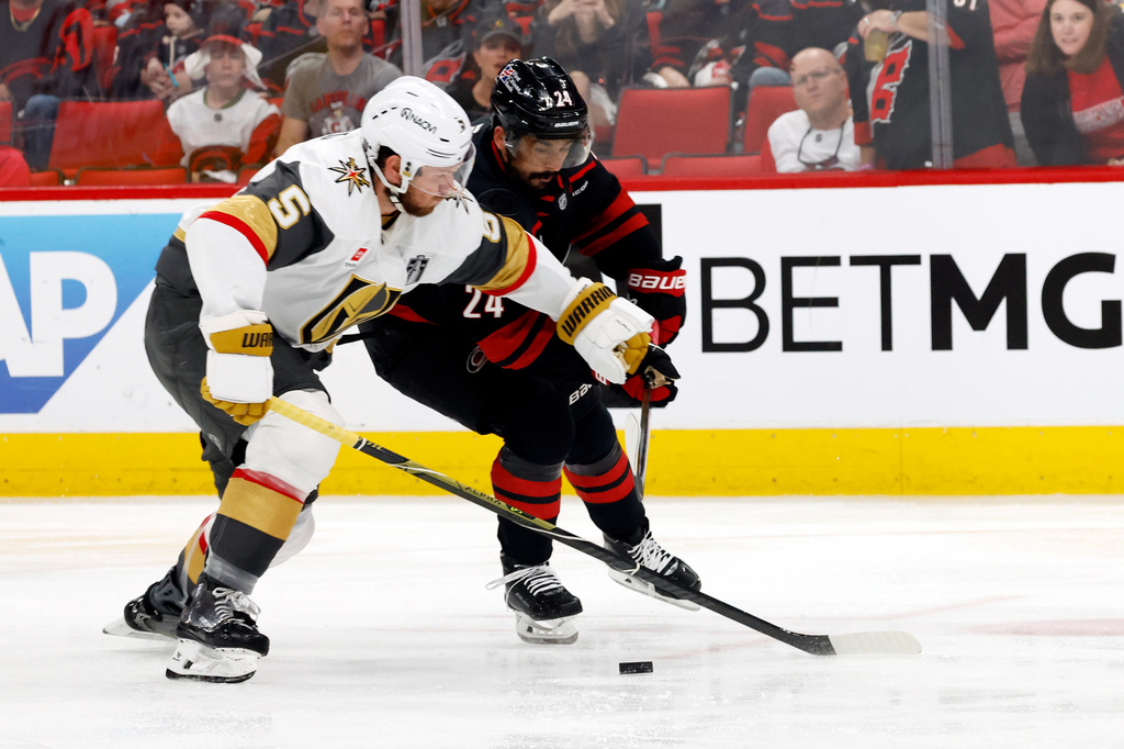 Carolina Hurricanes' Seth Jarvis (24) battles with Vegas Golden Knights' Jeremy Lauzon (5) during the second period in Game 1 of the NHL hockey Stanley Cup Final series in Raleigh, N.C., Tuesday, June 2, 2026. (AP Photo/Karl DeBlaker)