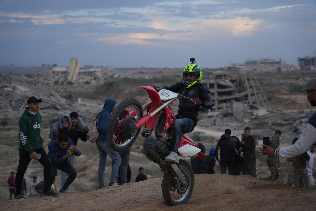 Palestinian Ahmed Abu Amra, 23, rides his motorcycle and shows off his skills on a sandy hill in the Al-Zahra area, central Gaza Strip, Friday, Dec. 5, 2025. (AP Photo/Abdel Kareem Hana)