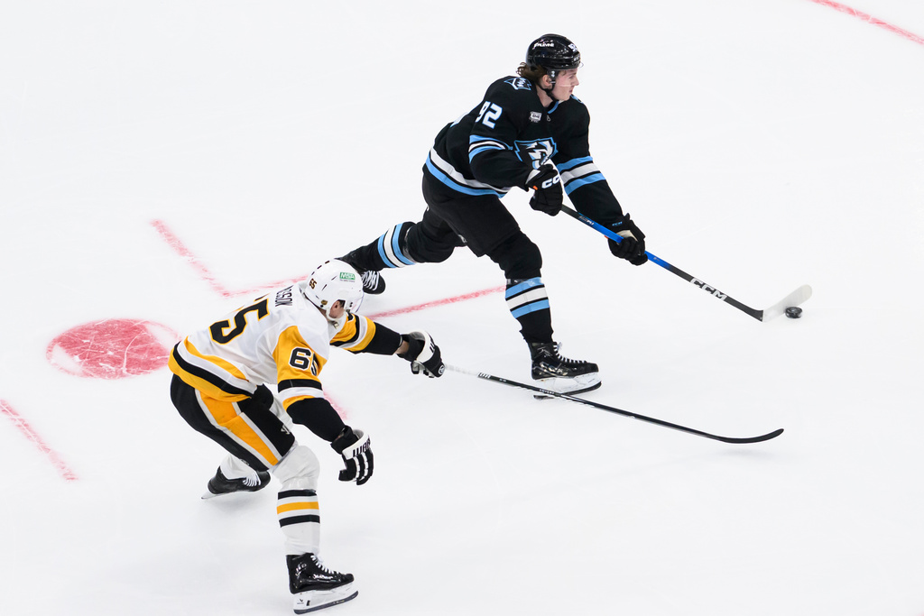 Utah Mammoth center Logan Cooley, top, shoots the puck defended by Pittsburgh Penguins defenseman Erik Karlsson, bottom, during the first period of an NHL hockey game Saturday, March 14, 2026, in Salt Lake City. (AP Photo/Tyler Tate)