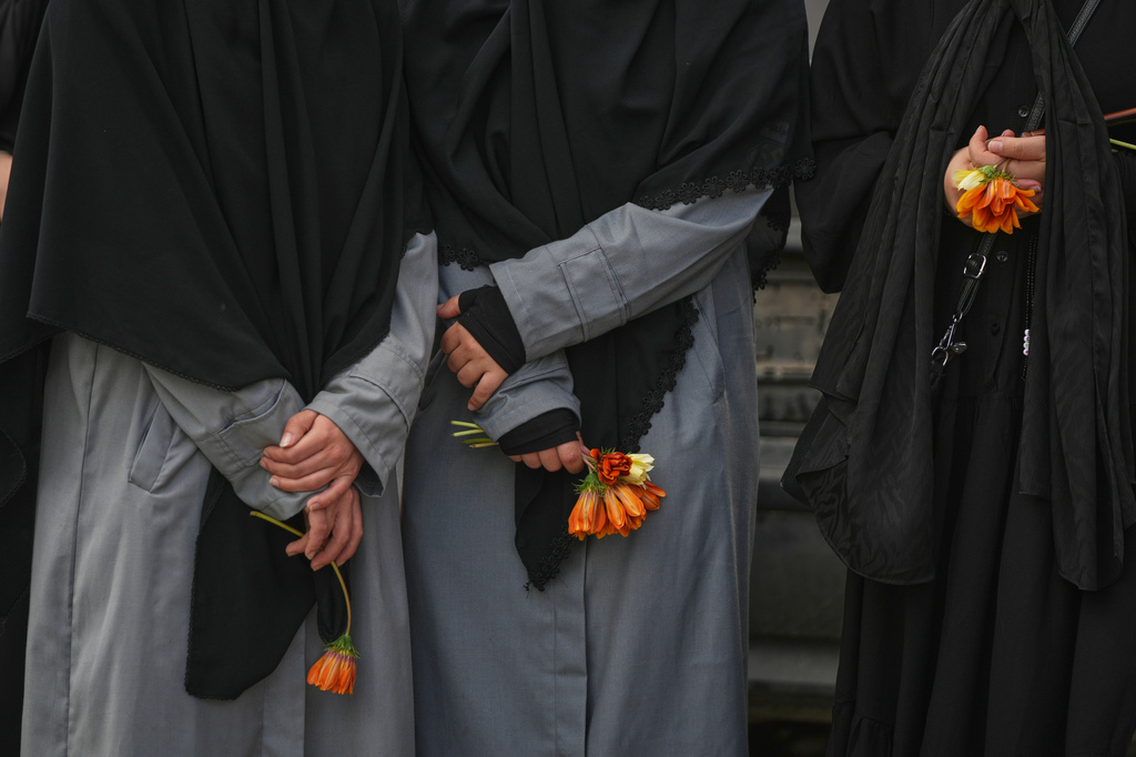 Women hold flowers during a mass funeral procession for Hezbollah fighters killed before the ceasefire in the war with Israel in the southern village of Kfar Sir, Lebanon, Tuesday, April 21, 2026. (AP Photo/Hassan Ammar)