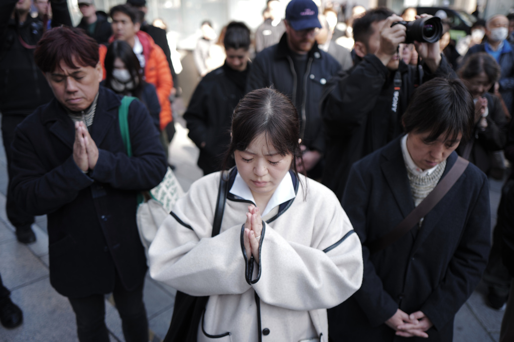 Bystanders pray at 2:46 p.m., Wednesday, March 11, 2026 in Tokyo, as Japan marked the 15th anniversary of the 2011 earthquake, tsunami, and nuclear disaster that devastated the northeastern coast. (AP Photo/Eugene Hoshiko)