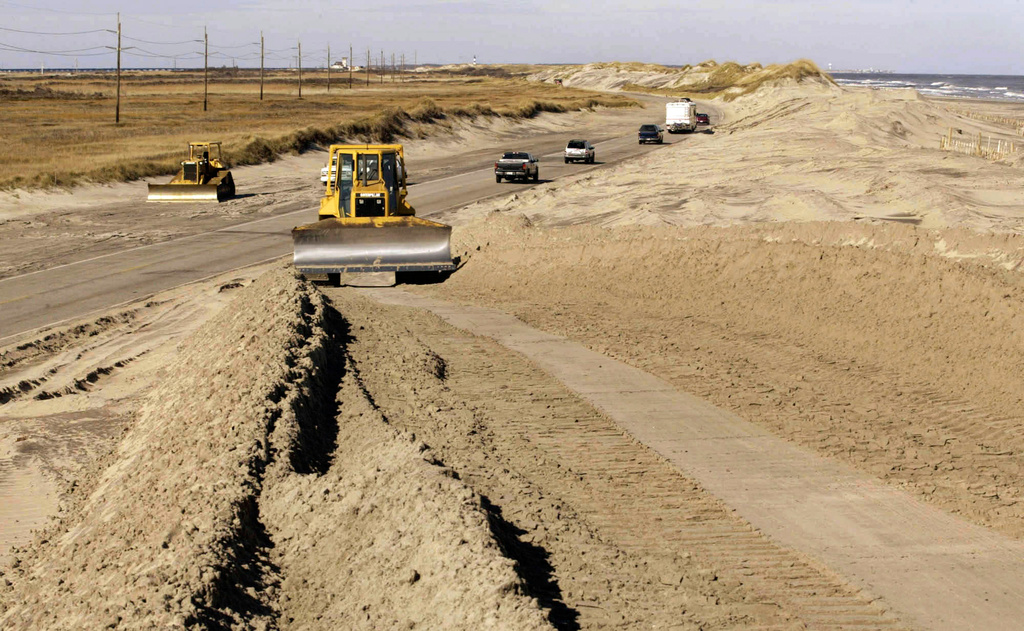 FILE - A bulldozer pushes sand along NC highway 12 in the Pea island National Wildlife Refuge, on North Carolina's Outer Banks, near Nags Head, N.C., Dec. 18, 2003, as workers rebuild dunes that were destroyed by Hurricane Isabel. (AP Photo/Bob Jordan, File)
