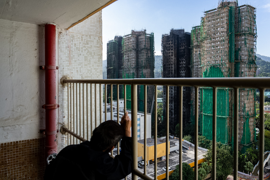 A resident looks at the burned buildings after deadly fires at Wang Fuk Court, a residential estate in the Tai Po district of Hong Kong's New Territories, Friday, Nov. 28, 2025. (AP Photo/Chan Long Hei)