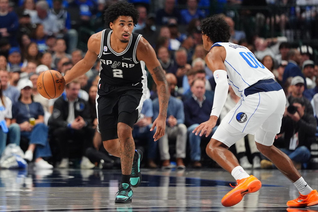 San Antonio Spurs guard Dylan Harper (2) dribbles against Dallas Mavericks guard Max Christie (00) during the first half of an NBA basketball game in Dallas, Wednesday, Oct. 22, 2025. (AP Photo/LM Otero)