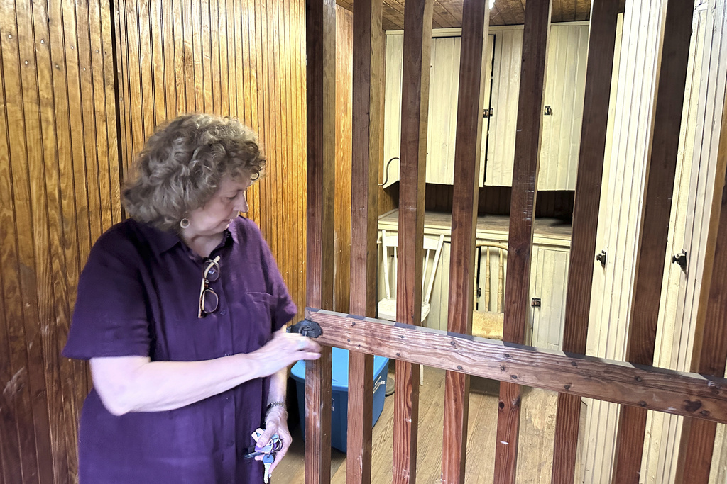 Local historian Sue Hostetter opens the door to the rarely used jail cell with wooden bars on the second floor of the Hall of Philosophy, Wednesday, Aug. 6, 2025, in Mount Gretna, Pa. (AP Photo/Mark Scolforo)