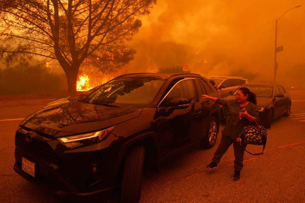 FILE - A woman cries as the Palisades Fire advances in the Pacific Palisades neighborhood of Los Angeles, Jan. 7, 2025. (AP Photo/Etienne Laurent, File)