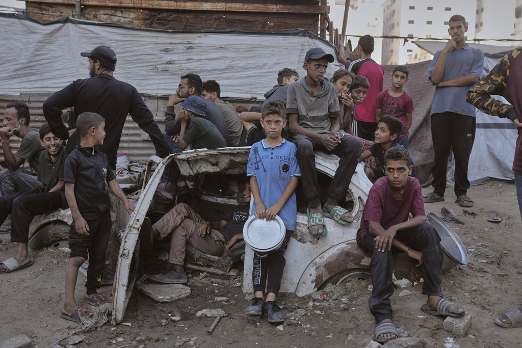 Palestinians wait for donated food at a community kitchen in Gaza City, in the northern Gaza Strip, July 14, 2025. (AP Photo/Jehad Alshrafi)