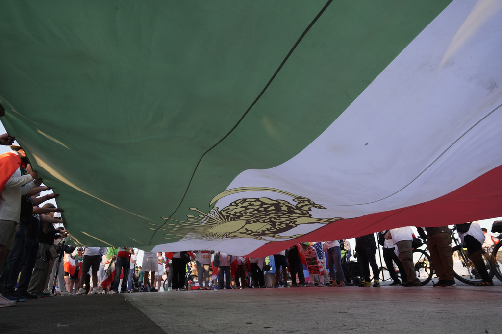 People unfurl a large Pre-revolutionary Iranian flag during a protest outside Los Angeles Stadium before the World Cup Group G soccer match between Iran and New Zealand in Inglewood, Calif., near Los Angeles, Monday, June 15, 2026. (AP Photo/Ty ONeil)