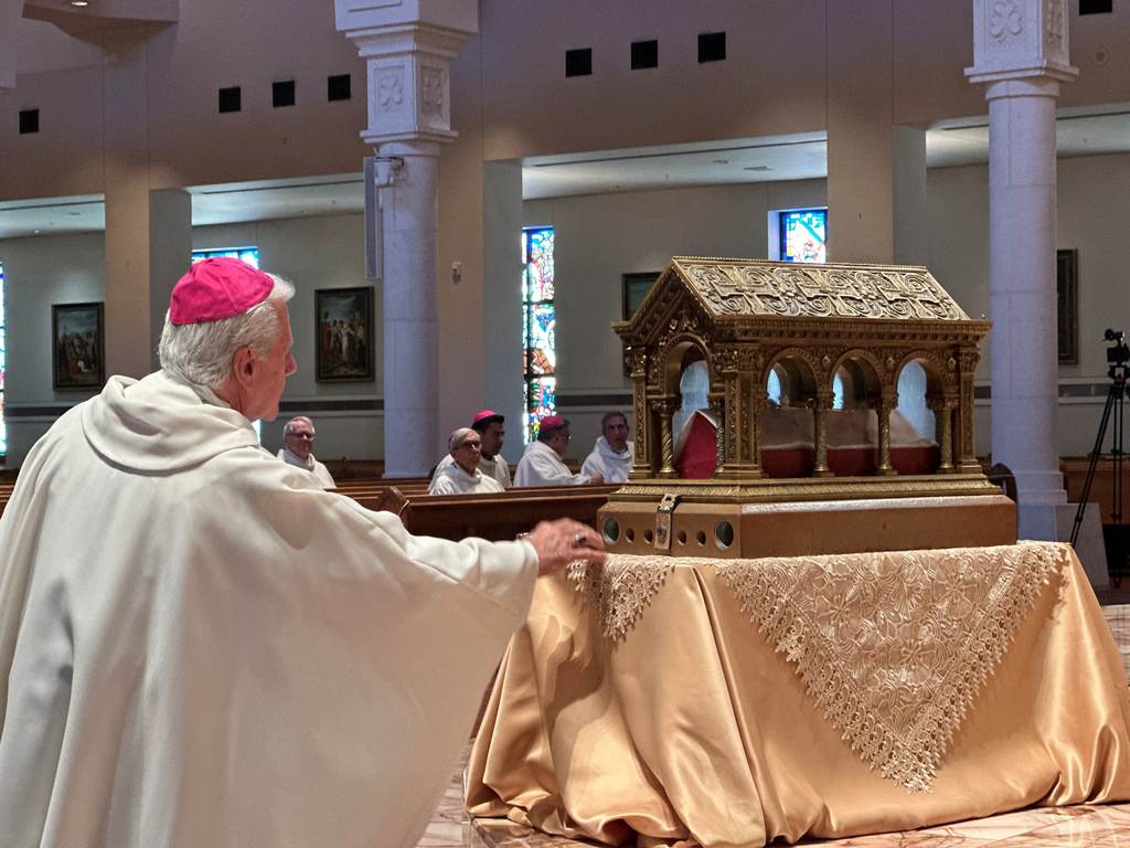 A bishop venerates relics of the 17th century St. Mary Margaret Alacoque, a French nun whose reports of visions of Jesus has led to the modern devotion of the Sacred Heart of Jesus, in front of the Basilica of the National Shrine of Mary, Queen of the Universe in Orlando, Fla., before a service Thursday, June 11, 2026, in which U.S. Catholic bishops consecrated the United States to the Sacred Heart upon the nation's 250th anniversary. (AP Photo/Peter Smith)