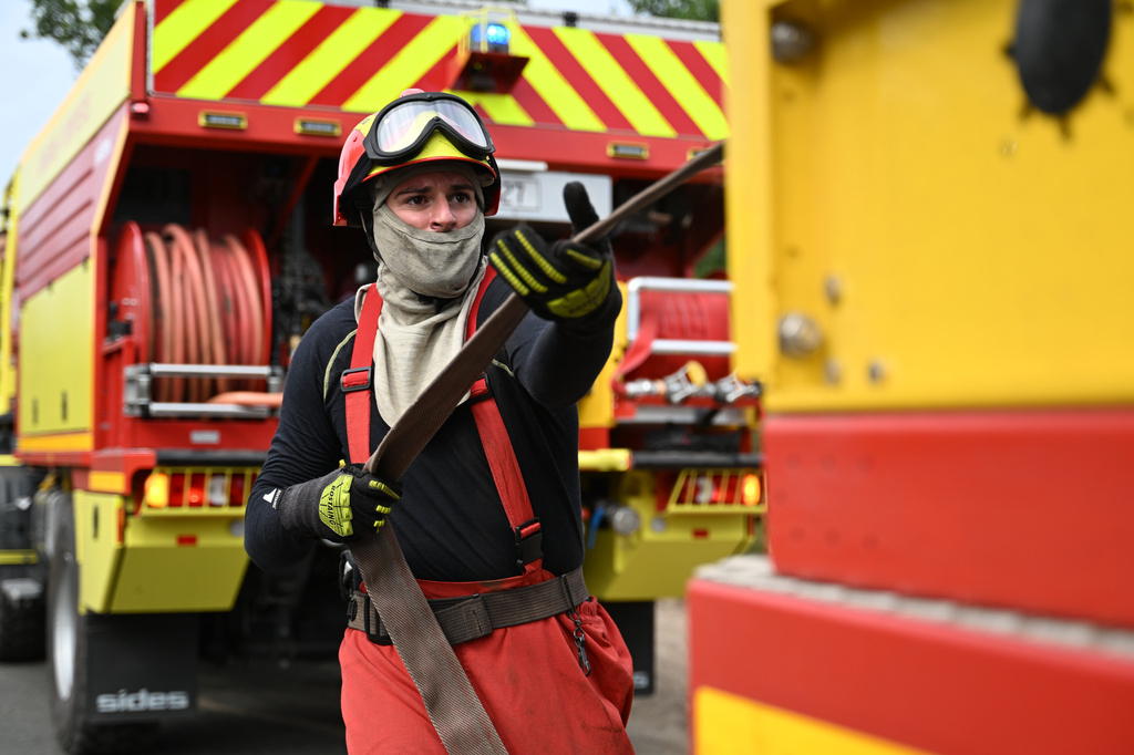 A firefighter unrolls a hose as he battles fires near Lege-Cap-Ferret, southwestern France, Friday, July 31, 2026. (AP Photo/Emma Da Silva)