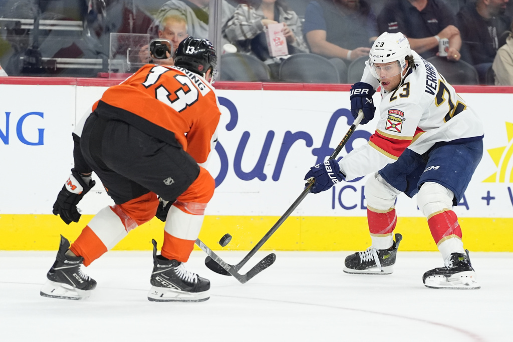 Florida Panthers' Carter Verhaeghe, right, passes the puck past Philadelphia Flyers' Adam Ginning, left, during the first period of an NHL hockey game, Monday, Oct. 13, 2025, in Philadelphia. (AP Photo/Matt Rourke)