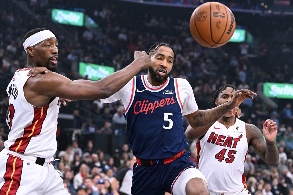 Miami Heat forward Bam Adebayo, left, and teammate Davion Mitchell (45) battle for the ball with Los Angeles Clippers forward Derrick Jones Jr. (5) during the first half of an NBA basketball game Monday, Nov. 3, 2025, in Los Angeles. (AP Photo/Wally Skalij)