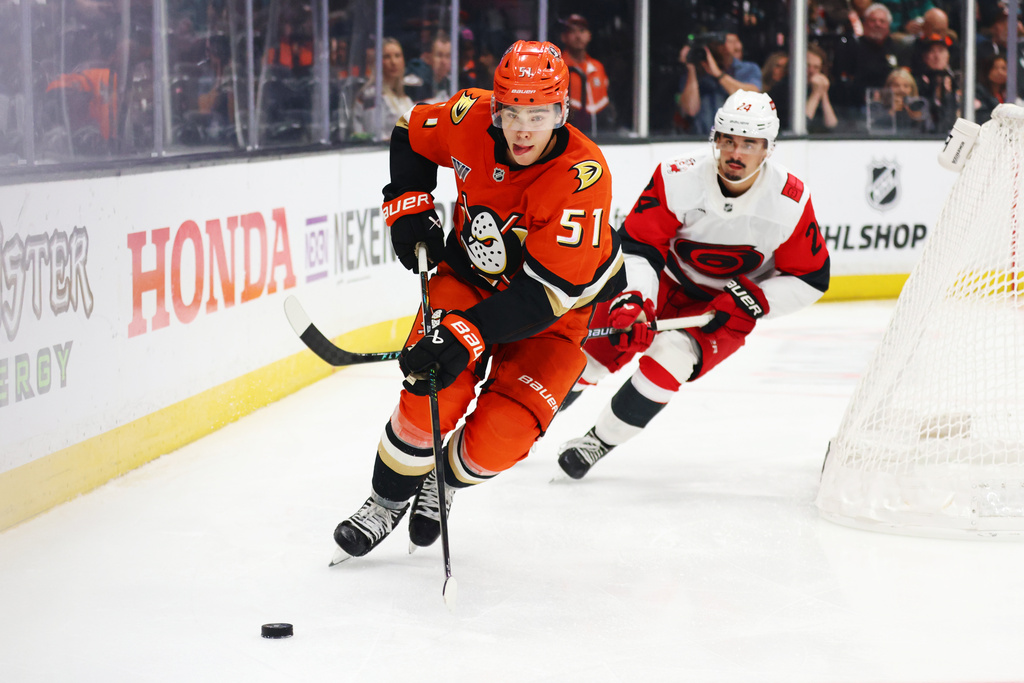 Anaheim Ducks defenseman Olen Zellweger (51) controls the puck against Carolina Hurricanes center Seth Jarvis (24) during the second period of an NHL hockey game Thursday, Oct. 16, 2025, in Anaheim, Calif. (AP Photo/Ethan Swope)