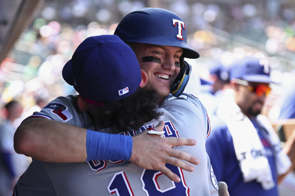 Texas Rangers' Josh Jung, right, hugs Alejandro Osuna, left, after hitting a solo home run during the second inning of a baseball game Sunday, Aug. 31, 2025, in West Sacramento, Calif. (AP Photo/Sara Nevis)