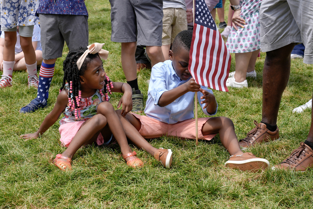 A child places an American flag in the ground at the Great American State Fair on the National Mall, Thursday, July 9, 2026, in Washington. (AP Photo/Mariam Zuhaib)