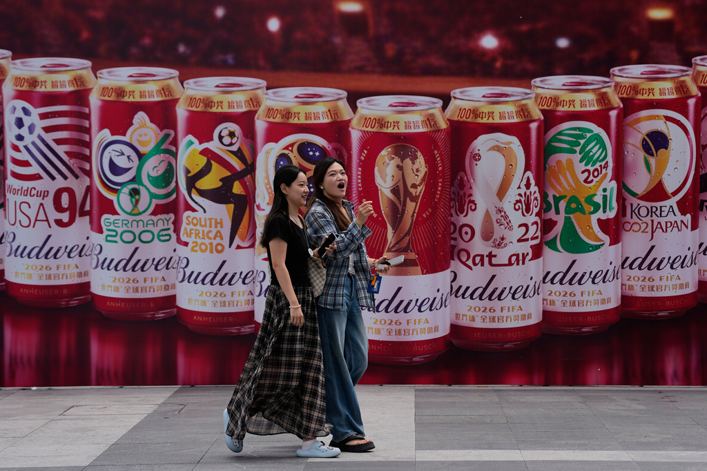Women walk by a promotional booth displaying Budweiser beer images for the 2026 World Cup, outside a shopping mall in Beijing, China on Tuesday, July 14, 2026. (AP Photo/Andy Wong)