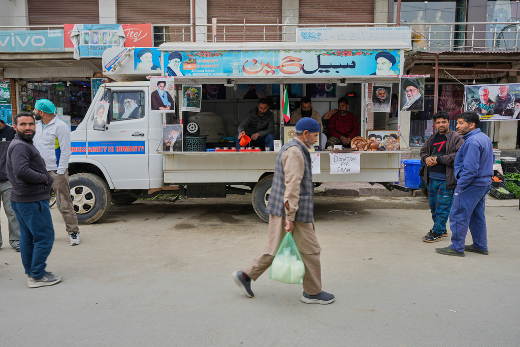 People walk past a van collecting donations for Iran in Budgam, Indian-controlled Kashmir, Monday, March 23, 2026. (AP Photo/Mukhtar Khan)