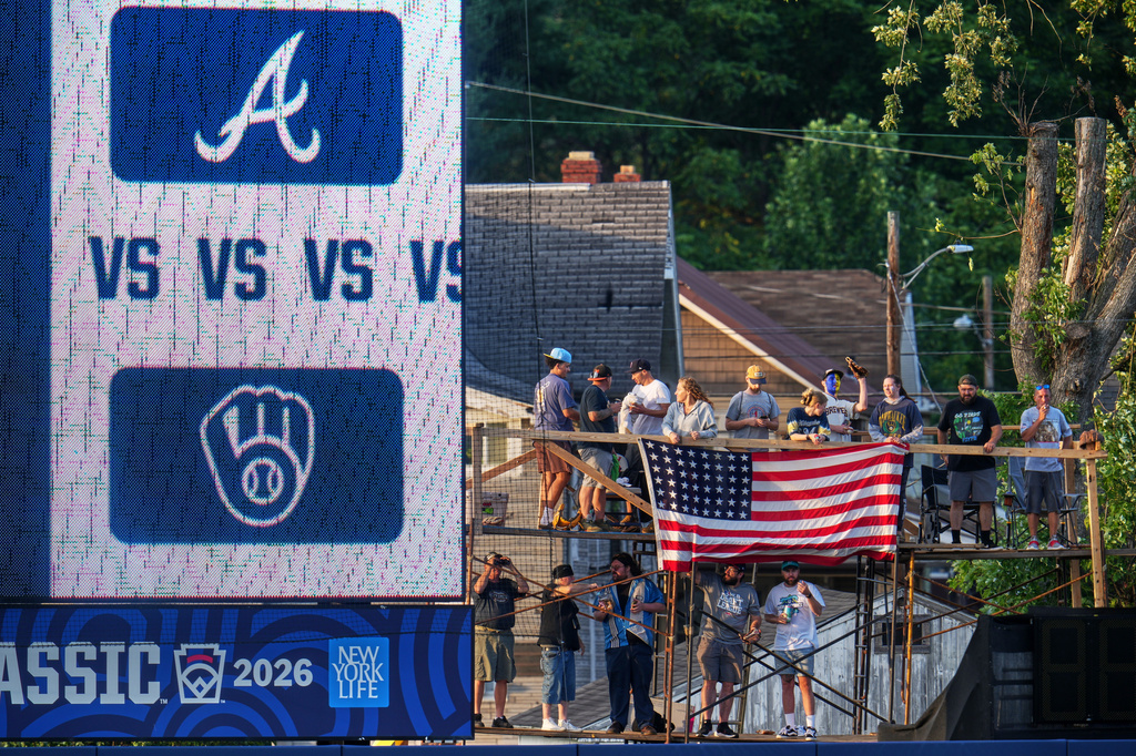 Fans on a scaffold beyond the outfield fence at Bowman Field watch the opening ceremony before the Little League Classic baseball game between the Milwaukee Brewers and the Atlanta Braves in Williamsport, Pa., Sunday, Aug. 23, 2026. (AP Photo/Gene J. Puskar)