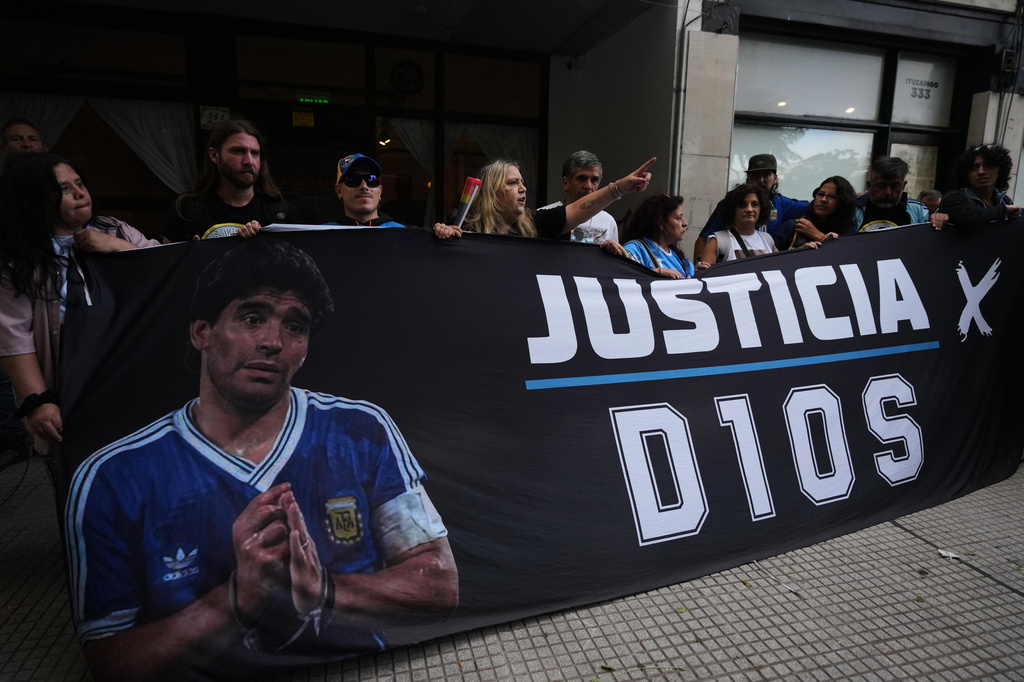 Fans of the late soccer star Diego Maradona stand outside court on the first day of the trial of his medical team for alleged homicide by negligence in San Isidro, Argentina, Tuesday, April 14, 2026. (AP Photo/Rodrigo Abd)