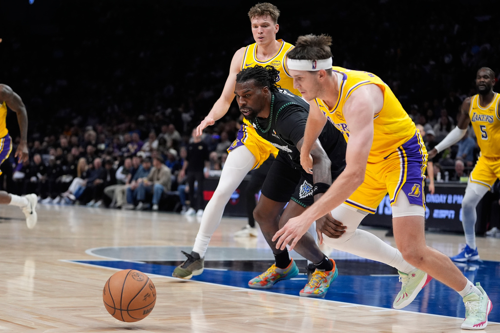 Minnesota Timberwolves center Naz Reid (11), middle, loses control of the ball as Los Angeles Lakers forward Dalton Knecht (4), back, and guard Austin Reaves (15), right, defend during the first half of an NBA basketball game, Wednesday, Oct. 29, 2025, in Minneapolis. (AP Photo/Abbie Parr)