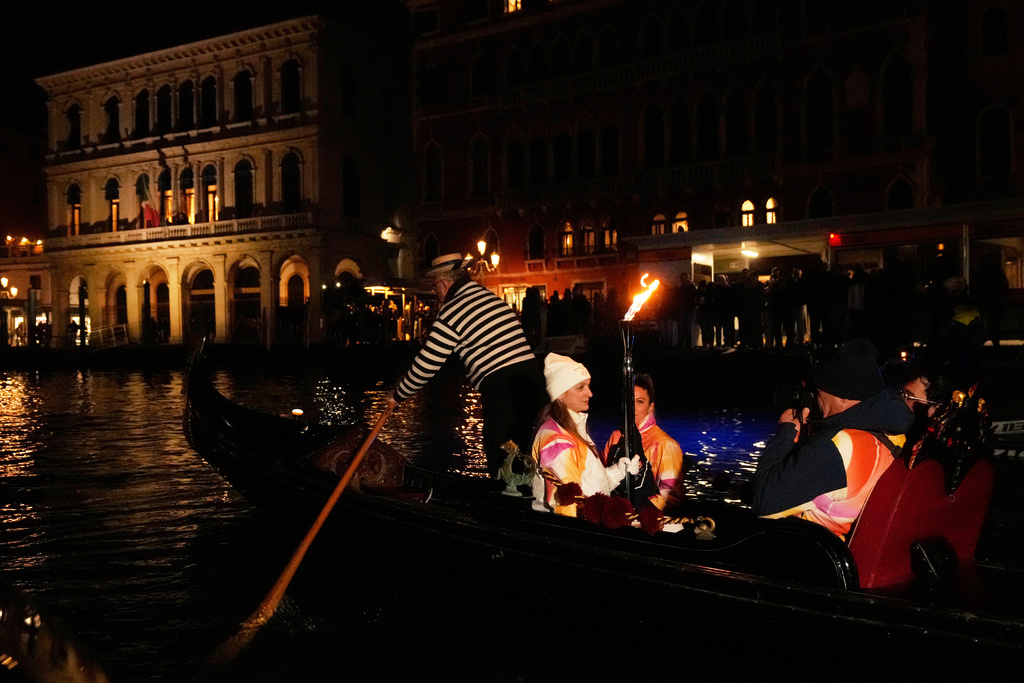 A torchbearer holds an Olympic torch flame on the Grand Canal in Venice, Italy, Thursday, Jan. 22, 2026, and its journey will conclude in Milan on February 6 for the Winter Olympics opening ceremony. (AP Photo/Luca Bruno)