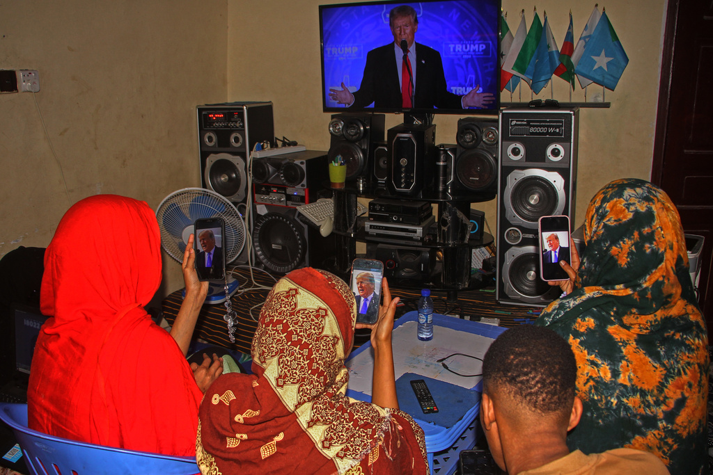 A Somali family watches a speech by U.S. president Donald Trump on their phones and on television, in Mogadishu, Somalia, Wednesday, Dec. 3, 2025. (AP Photo/Farah Abdi Warsameh)