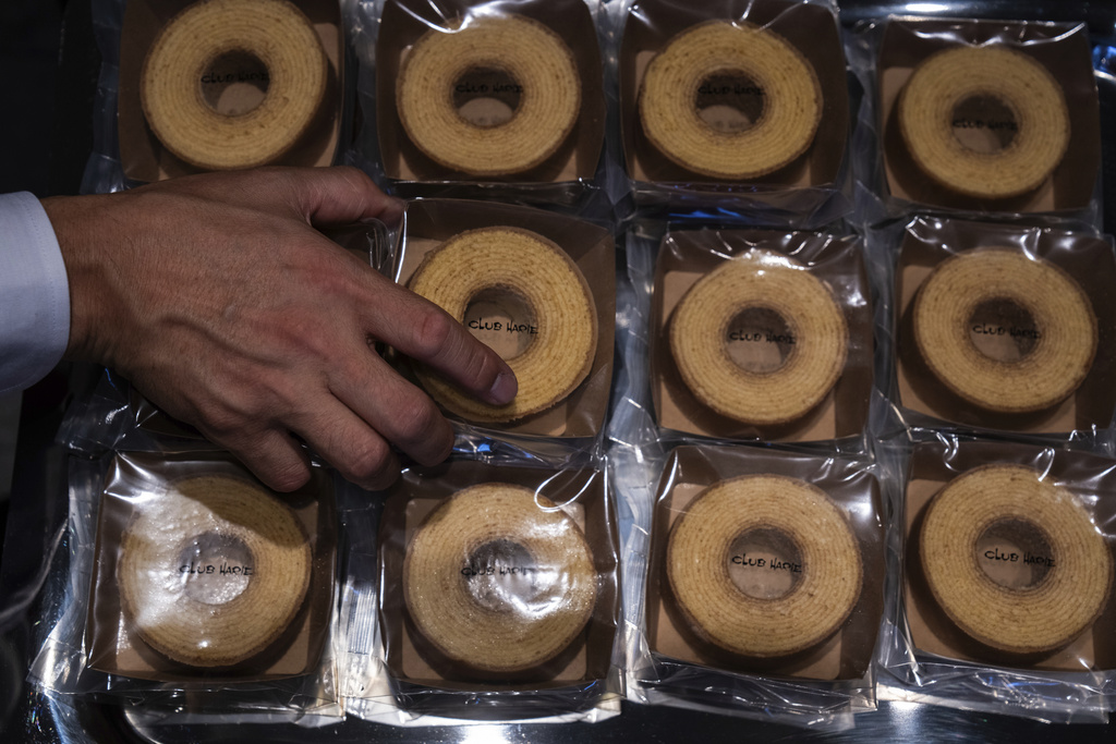 A vendor sorts articles at a baumkuchen store on its opening day in Tokyo, Friday, July 18, 2025. (AP Photo/Louise Delmotte)