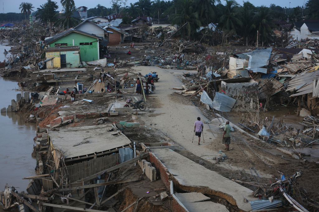 Survivors walk at an area affected by flash flood in Aceh Tamiang, on Sumatra Island, Indonesia, Thursday, Dec. 4, 2025. (AP Photo/Binsar Bakkara)