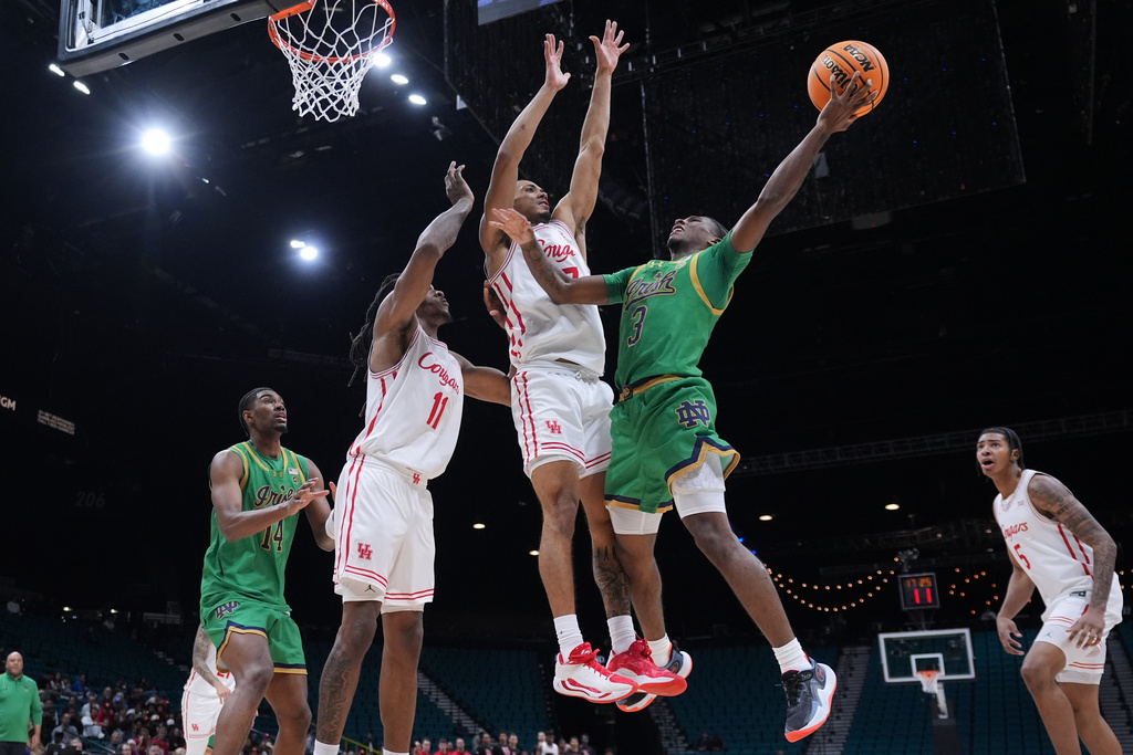 Notre Dame guard Markus Burton (3) drives to the basket against Houston guard Milos Uzan (7) and forward Joseph Tugler (11) during the second half of an NCAA college basketball game in the Players Era tournament in Las Vegas, Wednesday, Nov. 26, 2025. (AP Photo/Eric Gay)