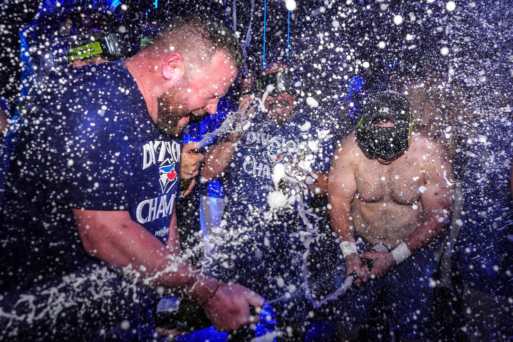 Toronto Blue Jays manager John Schneider, left, joins in with the team to celebrate after winning the American League East Division title following MLB baseball action against the Tampa Bay Rays, in Toronto, Sunday, Sept. 28, 2025. (Chris Young/The Canadian Press via AP)