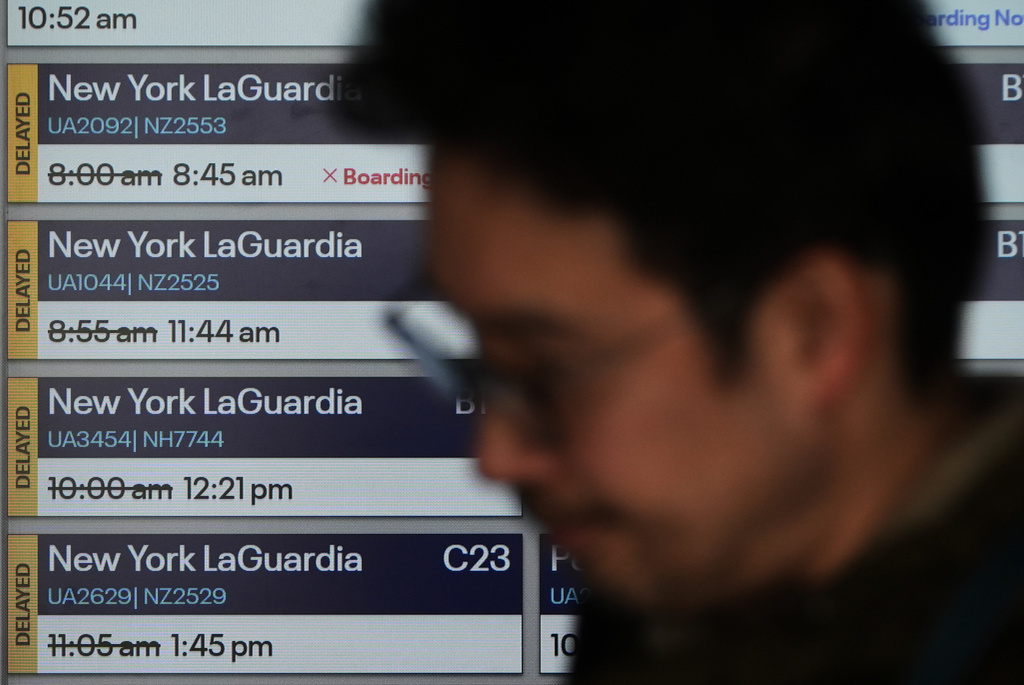 Delayed flight times are displayed at O'Hare International Airport in Chicago, Tuesday, March 24, 2026. (AP Photo/Nam Y. Huh)