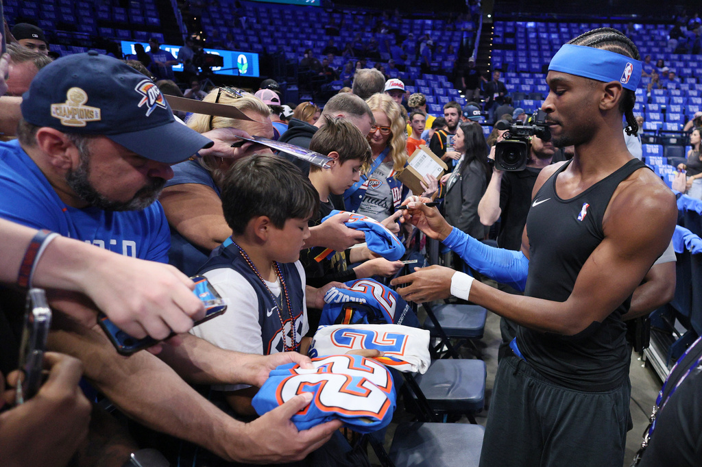 FILE - Oklahoma City Thunder guard Shai Gilgeous-Alexander, right, gives autographs to fans before Game 1 of a first-round NBA playoffs basketball series against the Phoenix Suns, Sunday, April 19, 2026, in Oklahoma City. (AP Photo/Nate Billings, File)