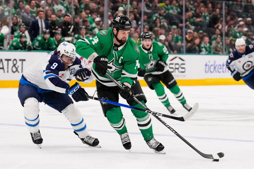 Dallas Stars left wing Jamie Benn (14) takes control of the puck in front of Winnipeg Jets' Alex Iafallo (9) in the first period of an NHL hockey game Thursday, April 2, 2026, in Dallas. (AP Photo/Tony Gutierrez)