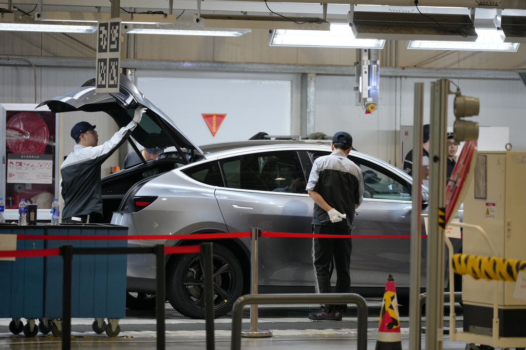 Workers check on the Tesla Model Y at the production lines at the Tesla Gigafactory assembly plant during a media organized tour, in Shanghai, China, Tuesday, April 14, 2026. (AP Photo/Andy Wong)