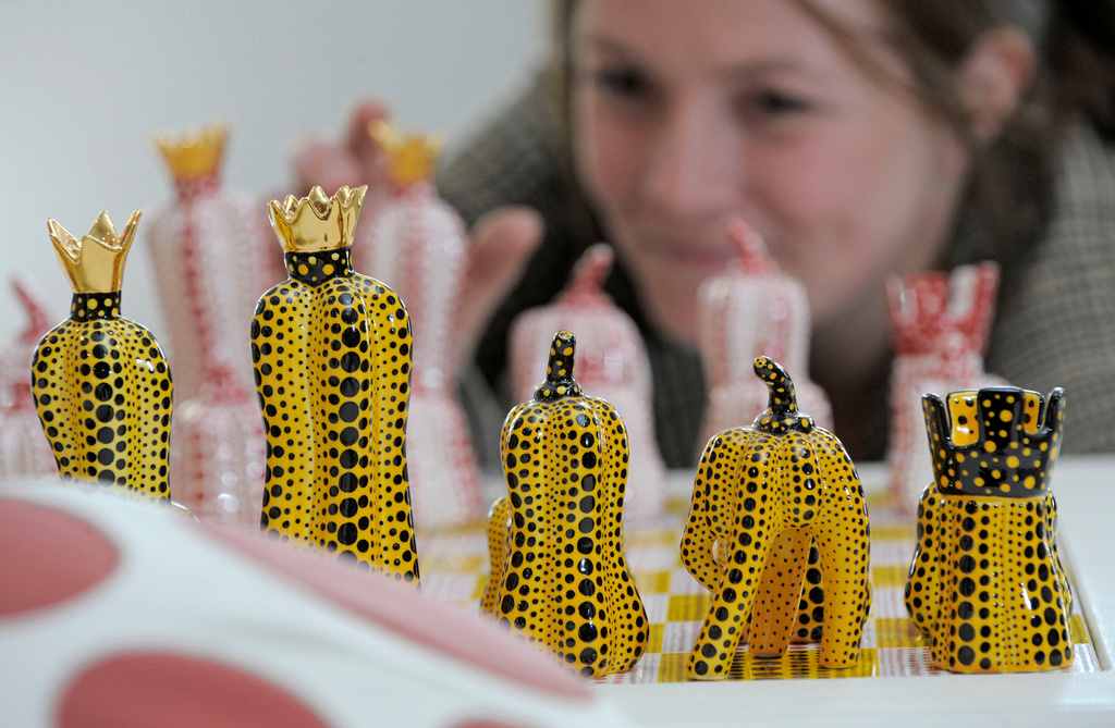 FILE - Exhibition assistant Kathrin DuBois of the Museum Ludwig in Cologne arranges chess board figures of the Japanese artist's Yayoi Kusama installation 'Pumpkin Chess' in the Porzellanikon Museum in Selb, southern Germany, on Thursday, April 22, 2010. (AP Photo/Jens Meyer, File)