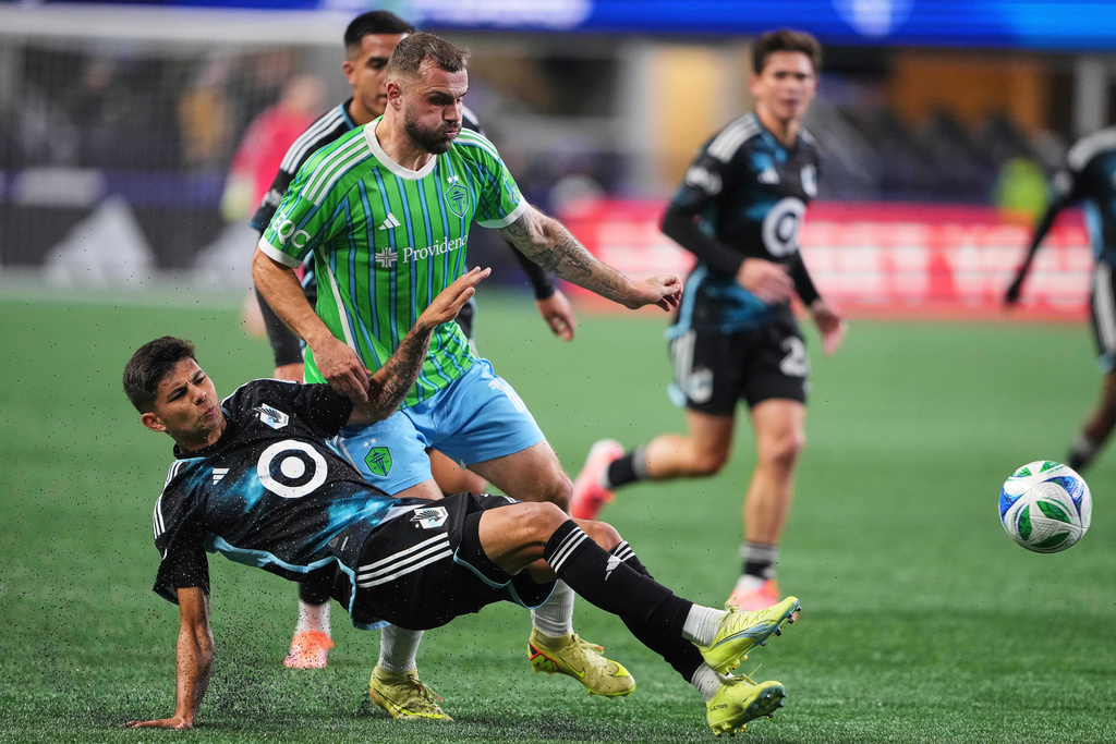 Minnesota United defender Anthony Markanich, front, falls against Seattle Sounders forward Jordan Morris during the first half of Game 2 in the first round of MLS soccer's Western Conference playoffs Monday, Nov. 3, 2025, in Seattle. (AP Photo/Lindsey Wasson)