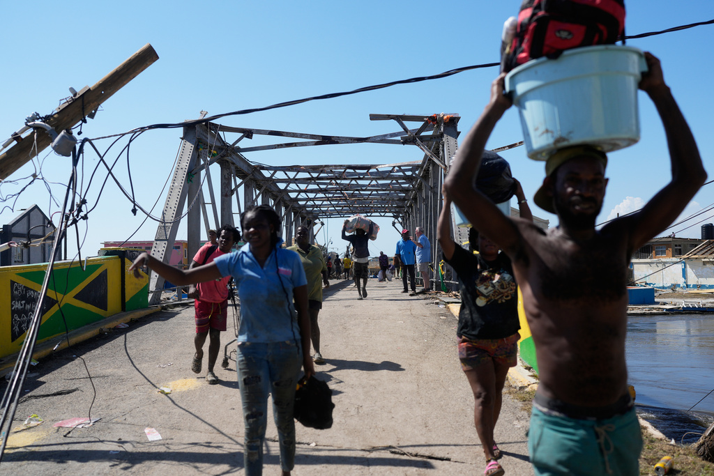 Residents leave Black River, Jamaica, Thursday, Oct. 30, 2025, after their homes were damaged by Hurricane Melissa. (AP Photo/Matias Delacroix)